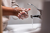 Mittelteil einer Frau beim Händewaschen