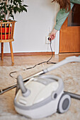 Woman plugging in vacuum cleaner