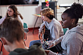 Teenagers attending guitar lesson