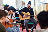 Teenagers attending guitar lesson