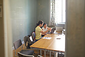 Coworkers in boardroom using laptop