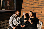 Großmutter mit erwachsenen Enkelkindern beim Selfie machen