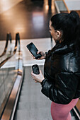 Woman using cell phone at escalator