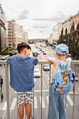 Children standing on viaduct and looking at traffic