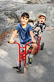 Portrait of child friends riding tricycle