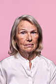 Portrait of senior woman against pink background