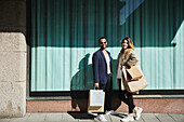 Friends standing on sidewalk with shopping bags