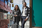 Portrait of man and woman with luggage in city center
