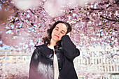 Young woman standing under cherry blossom