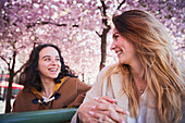 Lächelnde junge Frau unter Kirschblüten stehend