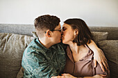 Weibliches Paar küsst sich auf dem Sofa