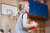 Mädchen hält Ball während des Sportunterrichts in der Schulsporthalle