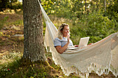 Woman using laptop in hammock