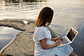 Woman using laptop at lake