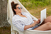 Woman using laptop on hammock