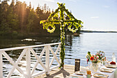 Midsummer maypole and set table by lake