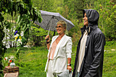Mann und Frau stehen im Regen neben dem Mittsommer-Maibaum