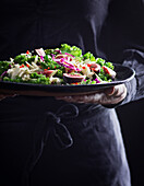 Frau hält frischen Salat auf einem Teller