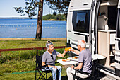 Älteres Paar beim Essen und Toast auf dem Campingplatz