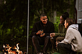 Freunde sitzen am Lagerfeuer und trinken Wein