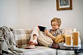 Boy on sofa using digital tablet