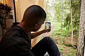 Mann sitzt im Wohnmobil und fotografiert den Wald