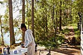 Woman collecting dishes from camping table