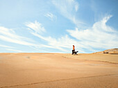 Woman walking dog at sand dune
