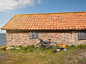 Cyclist relaxing near stone house at sea