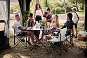 Friends with children relaxing under garden gazebo