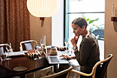 Geschäftsfrau arbeitet in einem Restaurant am Laptop