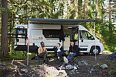 Friends relaxing in front of camper van