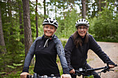 Portrait of female friends cycling in forest