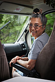 Portrait of smiling senior woman sitting in van