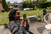 Lächelnde Frau mit Telefon im Garten