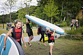 Mother and children carrying paddle boards