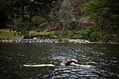 Mädchen schwimmt auf dem Rücken im See