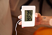 Woman holding thermostat at home
