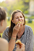 Lächelnde Frau isst Essen im Freien