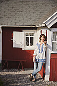 Smiling woman standing in front of wooden house