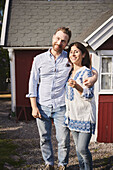 Smiling couple standing in front of wooden house
