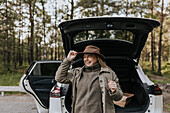 Laughing woman standing in front of car