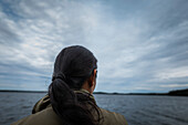 Black haired person looking at lake