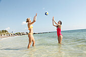 Freundinnen spielen Volleyball im Meer