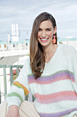 Young woman wearing a light knitted jumper with colorful stripes