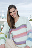 Young woman wearing a light knitted jumper with colorful stripes