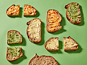 Slices of bread with various spreads on a green background