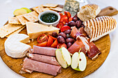 Cheese board with bread, ham and apple, olives and tomatoes