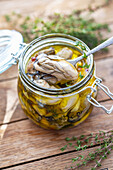 Jar of pickled oysters in olive oil with herbs and spices