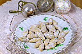 Vanillekipferl, arrangiert mit Weihnachtskugeln und Dekostern auf Spitzentischdecke